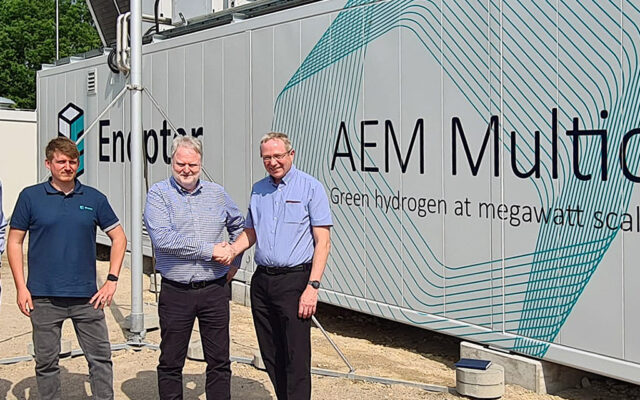 Enapter and Intelligent Energy in front of the AEM Multicore. Fom left to right: Martin Schaefer (Operations Director, Intelligent Energy Ltd.), Florian Vogt (Project Lead, Enapter), Sebastian-Justus Schmidt (CEO, Enapter AG), David Woolhouse (CEO, Intelligent Energy Ltd.)