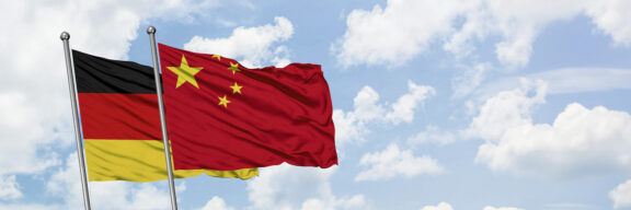 German and chinese flag with blue sky and white clouds in the background
